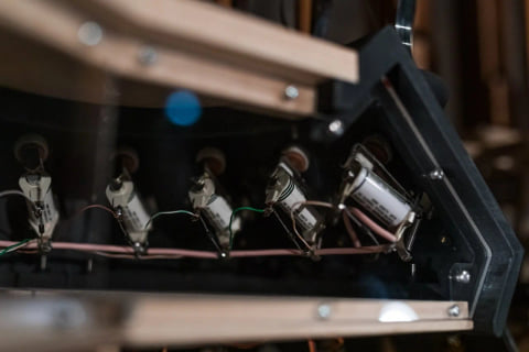 Close-up inside the instrument: a row of small wired actuators mounted on a wooden frame.