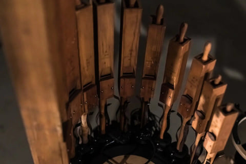 Close-up of a curved row of wooden organ pipes set into black robotic fittings.