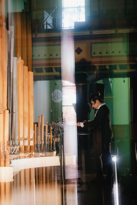 Navid Navab at the controls beside the tall pipes, framed by a shaft of light in a painted hall.