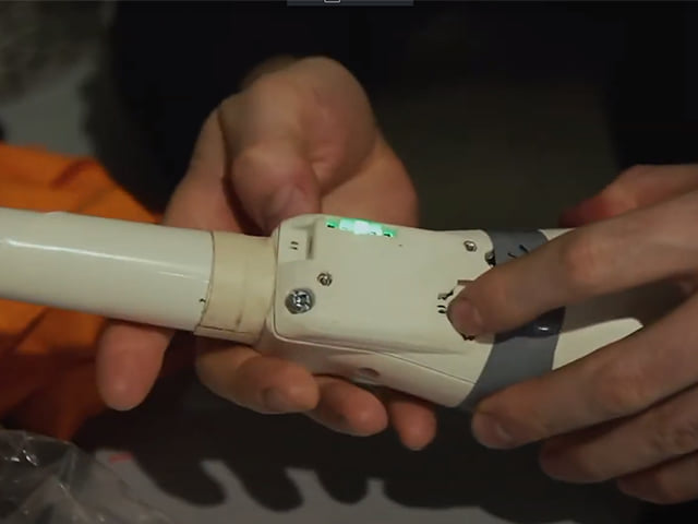 Hands holding a white juggling club with an electronic sensor module attached.