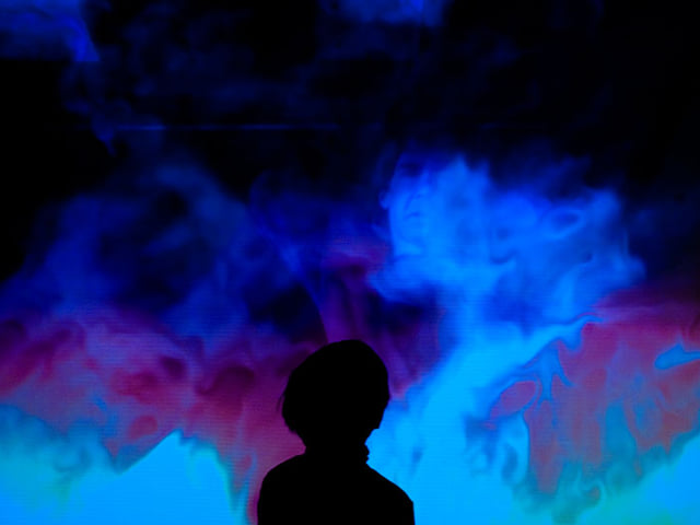 A child's silhouette against a swirling blue and violet fluid projection.
